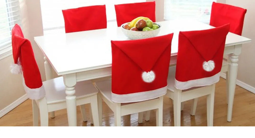 Dining table with chairs covered in Santa hats, set against a neutral wall.