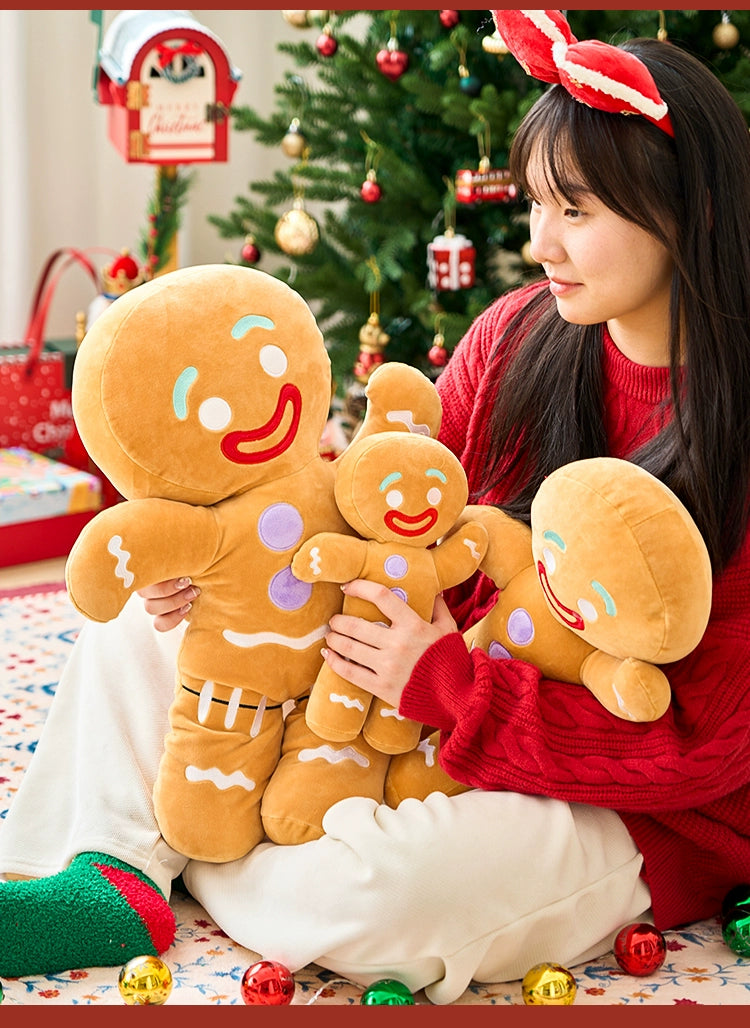 Person holding plush gingerbread men toys with a Christmas tree in the background
