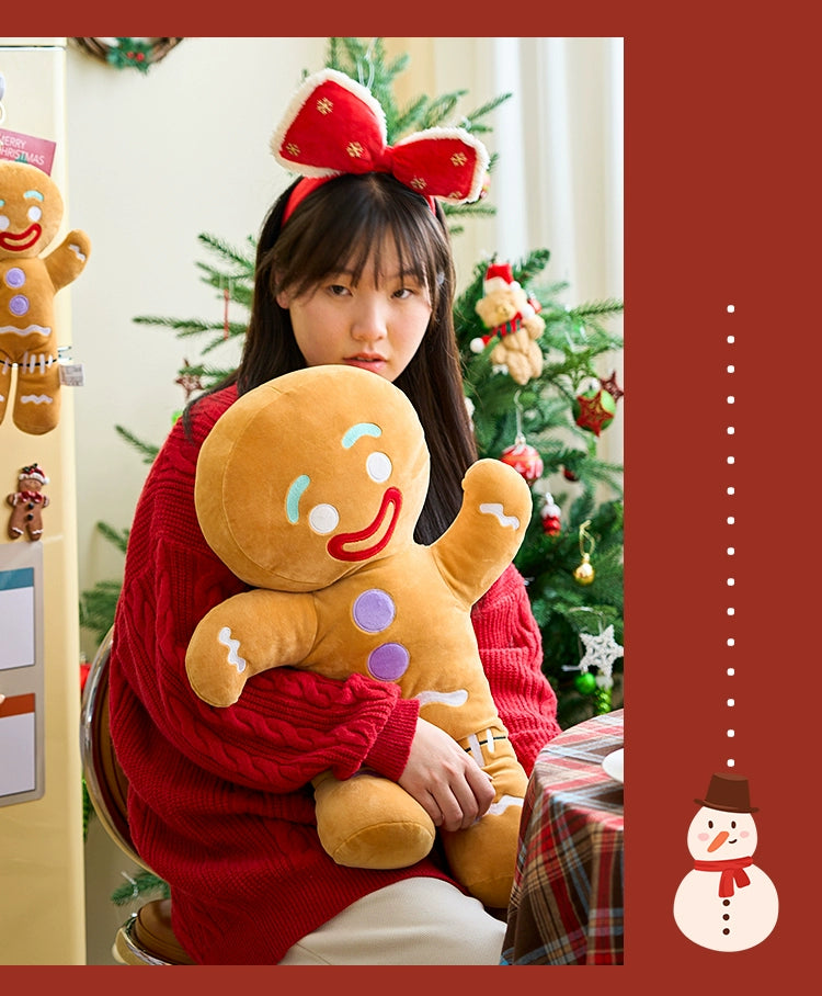 Person holding a gingerbread man plush toy with Christmas decorations in the background