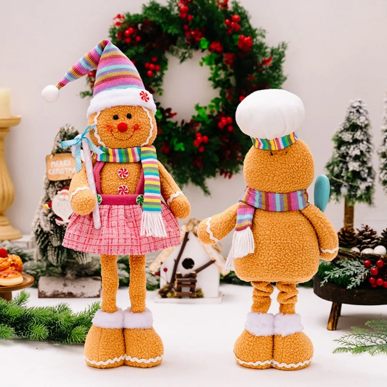 Two gingerbread-themed dolls with colorful hats and scarves in a festive setting.