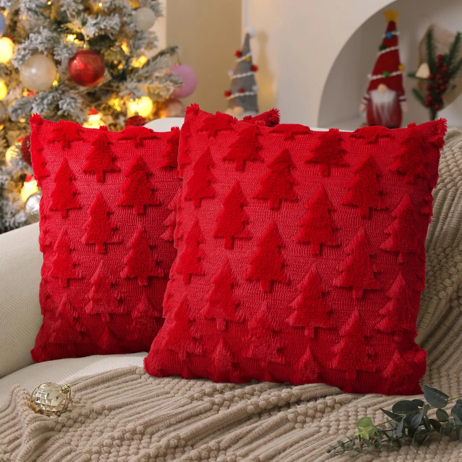 Red textured pillows on a couch with a Christmas tree and decorations in the background