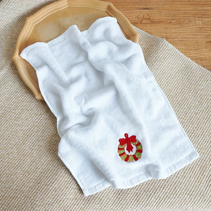 White towel with a embroidered wreath design on a wooden surface