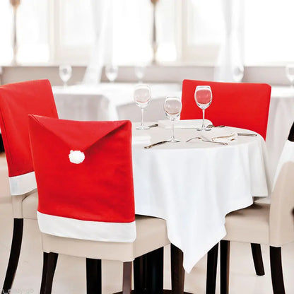 Dining table set with red Santa hat chair covers and white tablecloth.