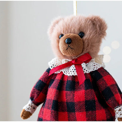 Teddy bear wearing a red and black checkered dress with a white collar on a light background
