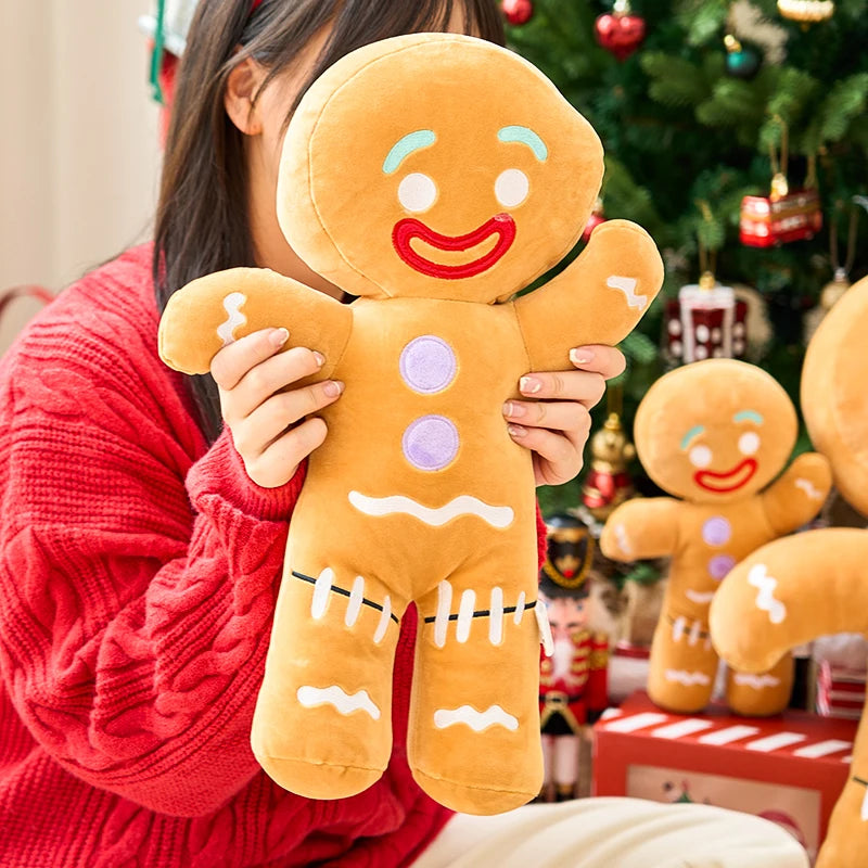 Person holding a plush gingerbread man toy with a Christmas tree in the background