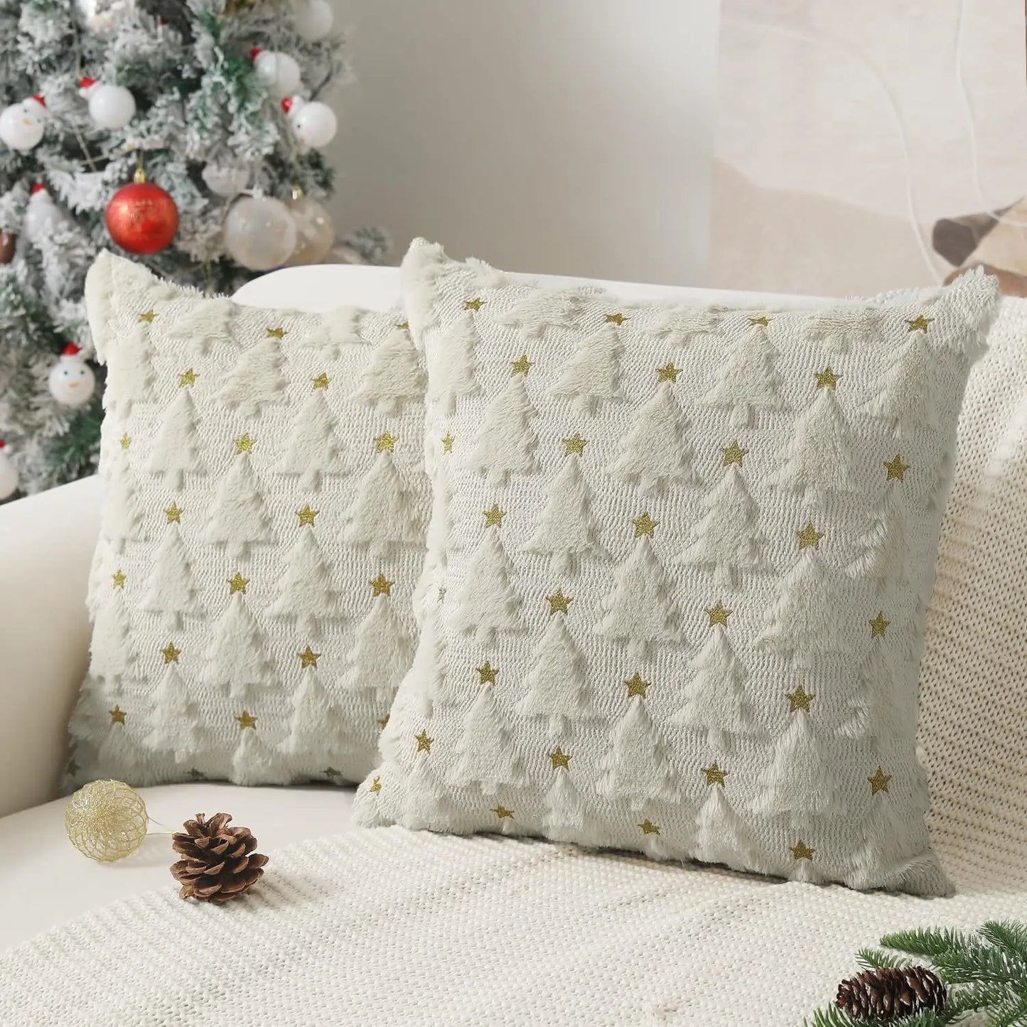 Decorative pillows with Christmas tree pattern on a couch next to a decorated Christmas tree.