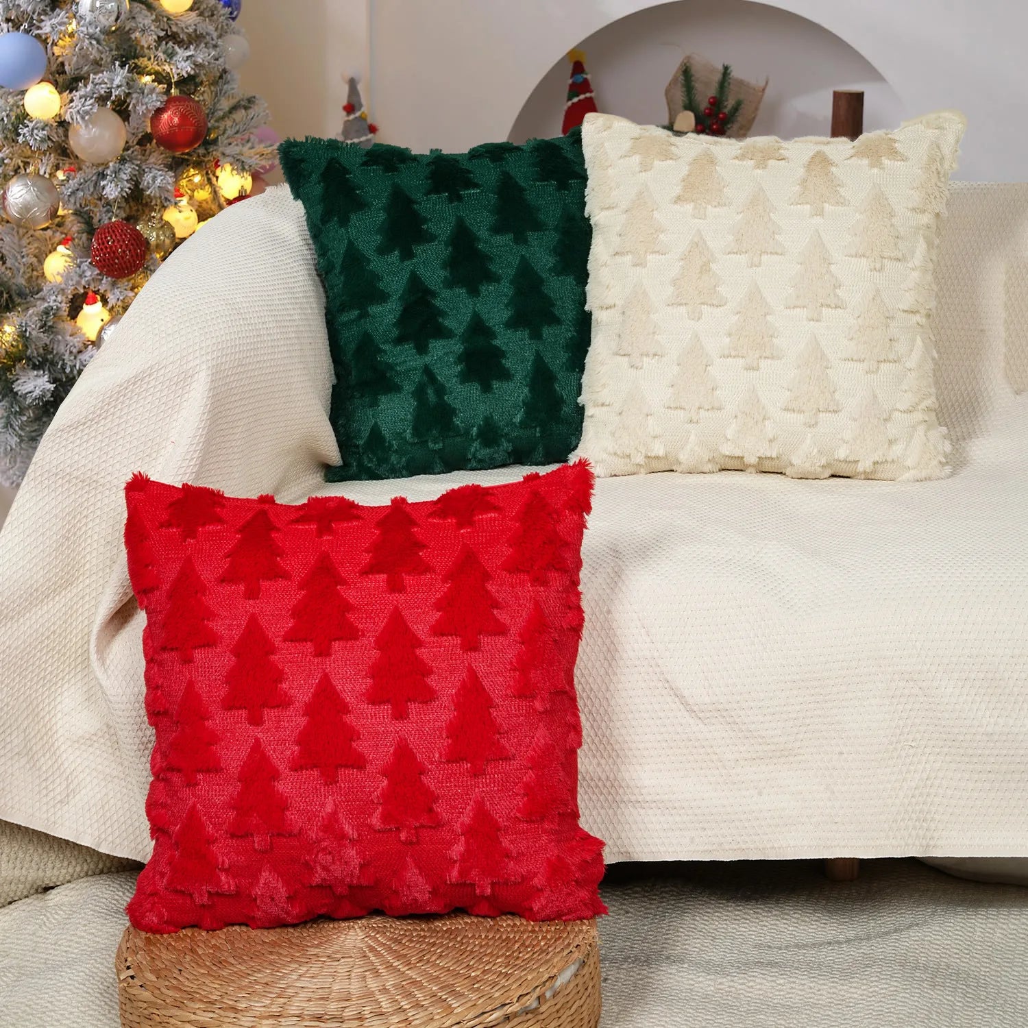 Decorative pillows with Christmas tree patterns on a couch next to a Christmas tree.