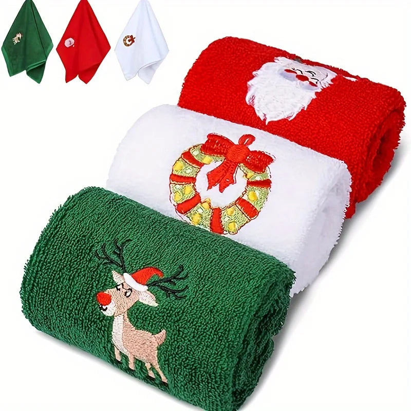 Set of Christmas-themed towels including a red Santa Claus towel, a green reindeer towel, and a white wreath towel.
