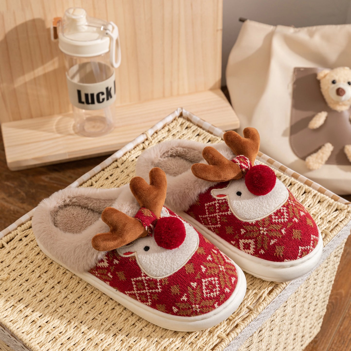 Red and white slippers with reindeer design on a woven mat