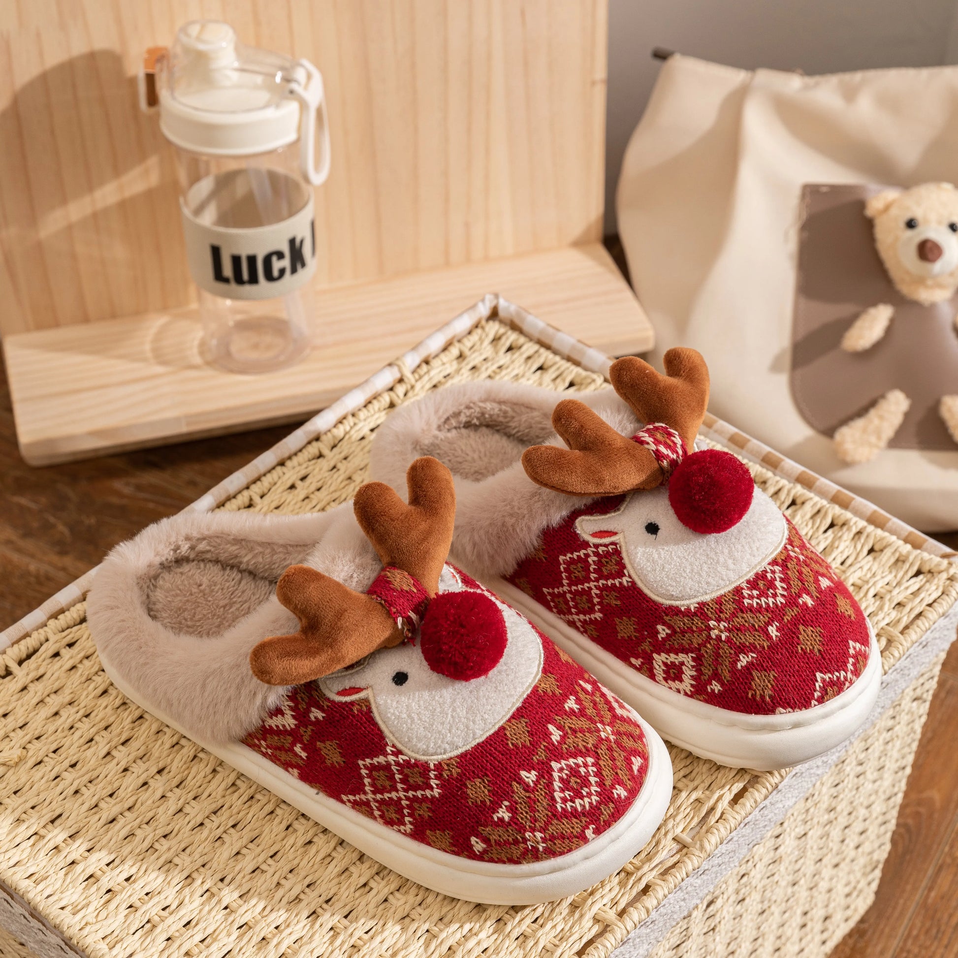 Red and white slippers with reindeer design on a woven mat