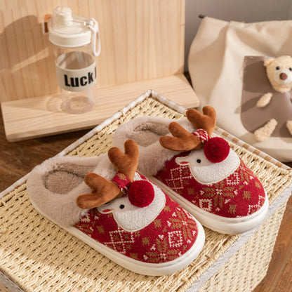 Red and white slippers with reindeer design on a woven mat