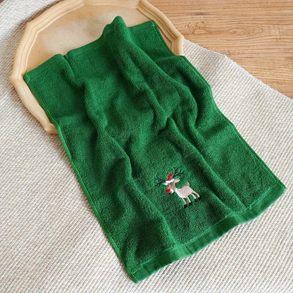 Green towel with a reindeer design on a wooden surface