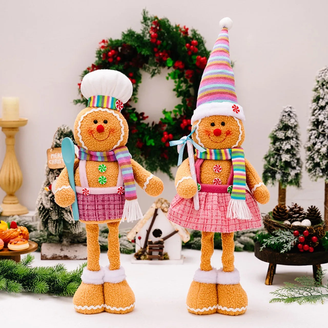 Two gingerbread-themed dolls with colorful hats and scarves in a festive setting.