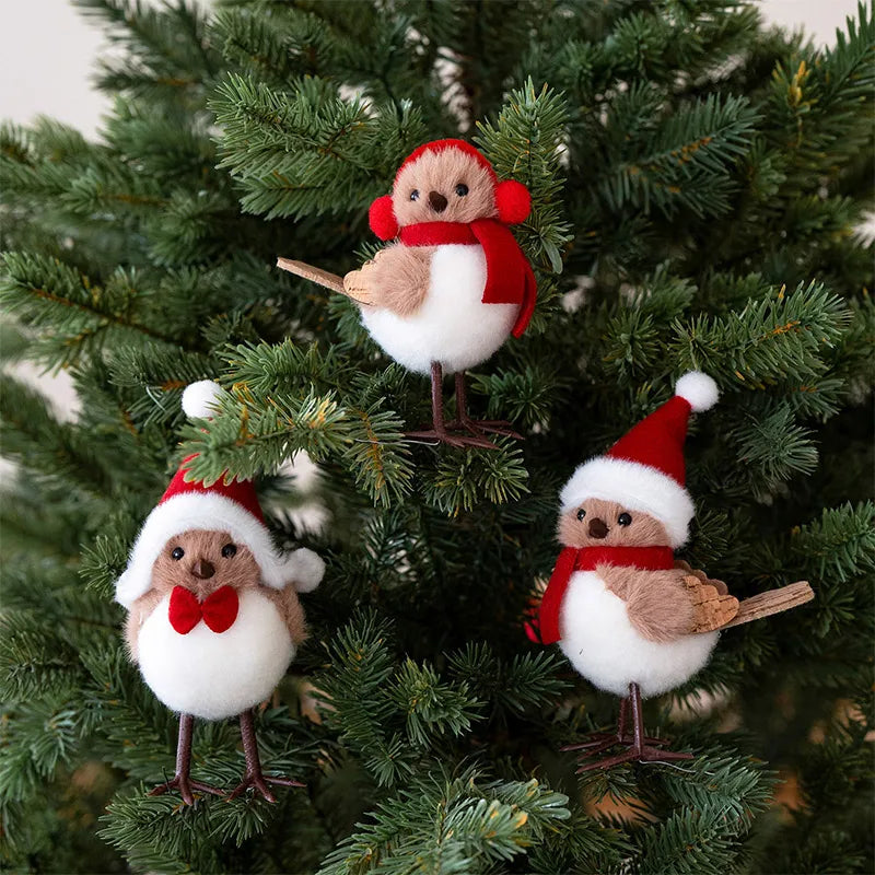 Three festive bird ornaments in red hats and scarves on a Christmas tree.