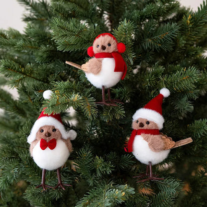 Three festive bird ornaments in red hats and scarves on a Christmas tree.
