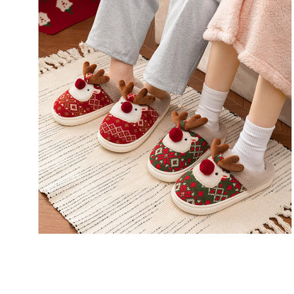 Children's red and green reindeer slippers worn indoors on a textured rug.
