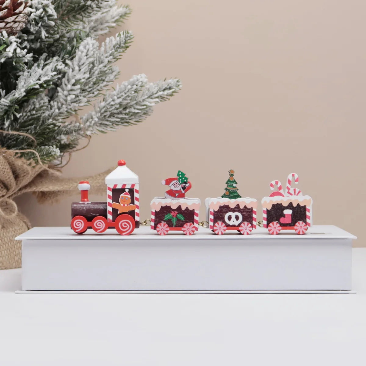 Set of Christmas-themed decorative items on a white surface with a tree in the background.