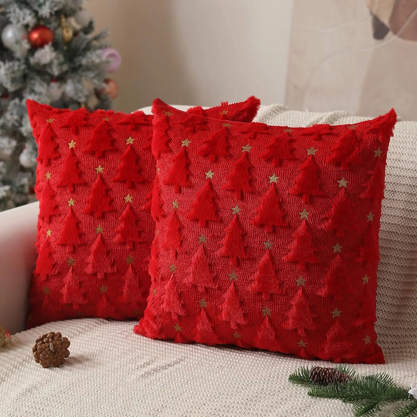 Red textured pillows with Christmas tree patterns on a couch with festive decorations.