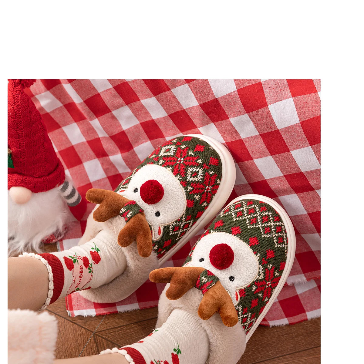 Christmas-themed slippers with reindeer design on a red and white checkered tablecloth.