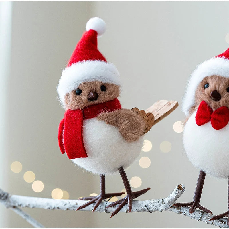 Two toy birds wearing Santa hats and scarves on a branch with a soft background.