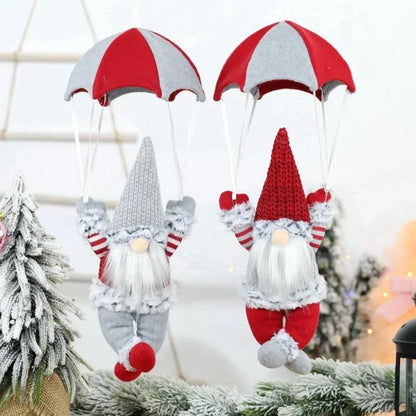 Two knitted gnomes with red and white hats hanging on a Christmas tree.
