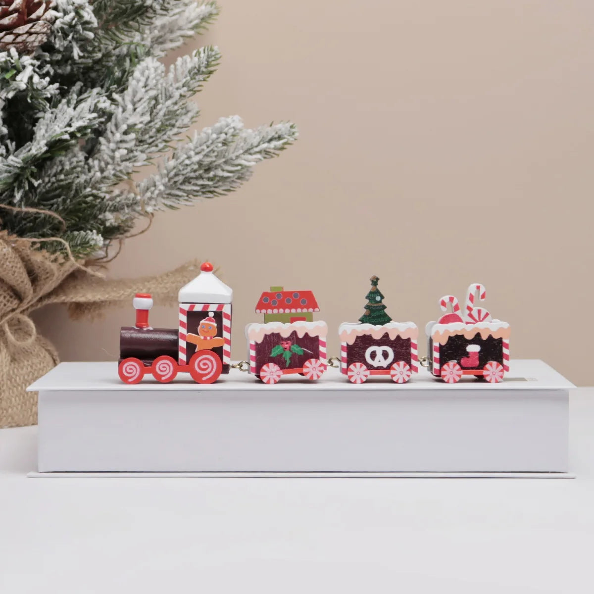 Set of decorative train figures on a white surface with a Christmas tree in the background.