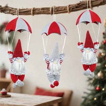 Three gnome ornaments with red and white striped parachutes hanging against a blurred indoor background.