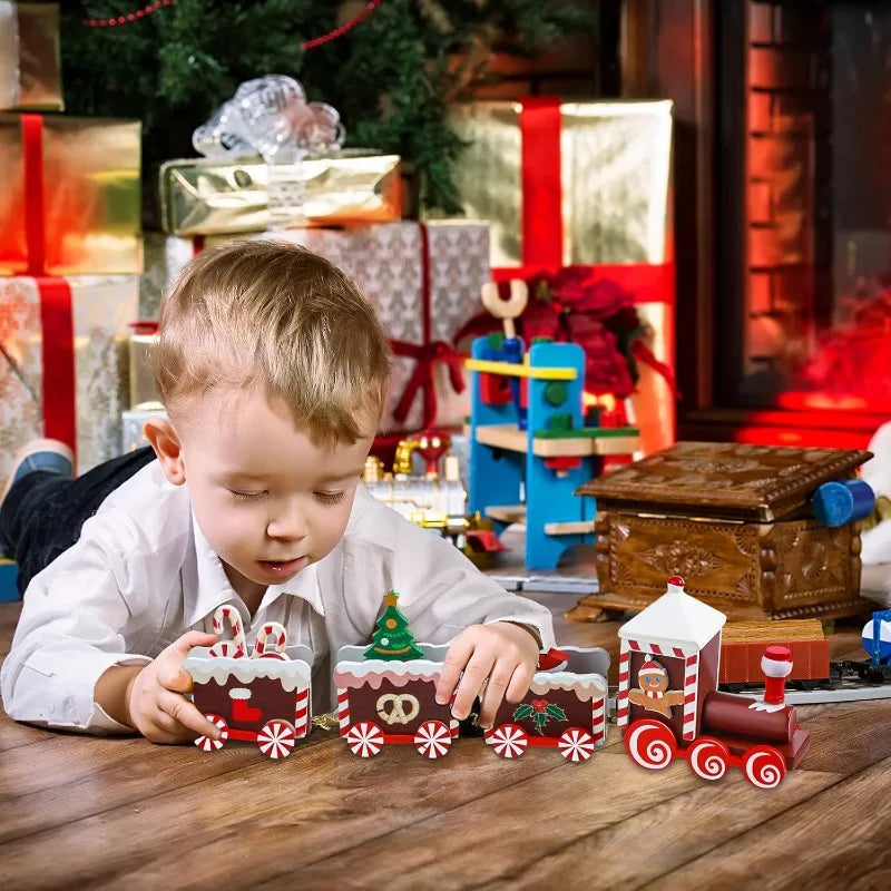 Child playing with a toy train set on a wooden table with Christmas decorations in the background.