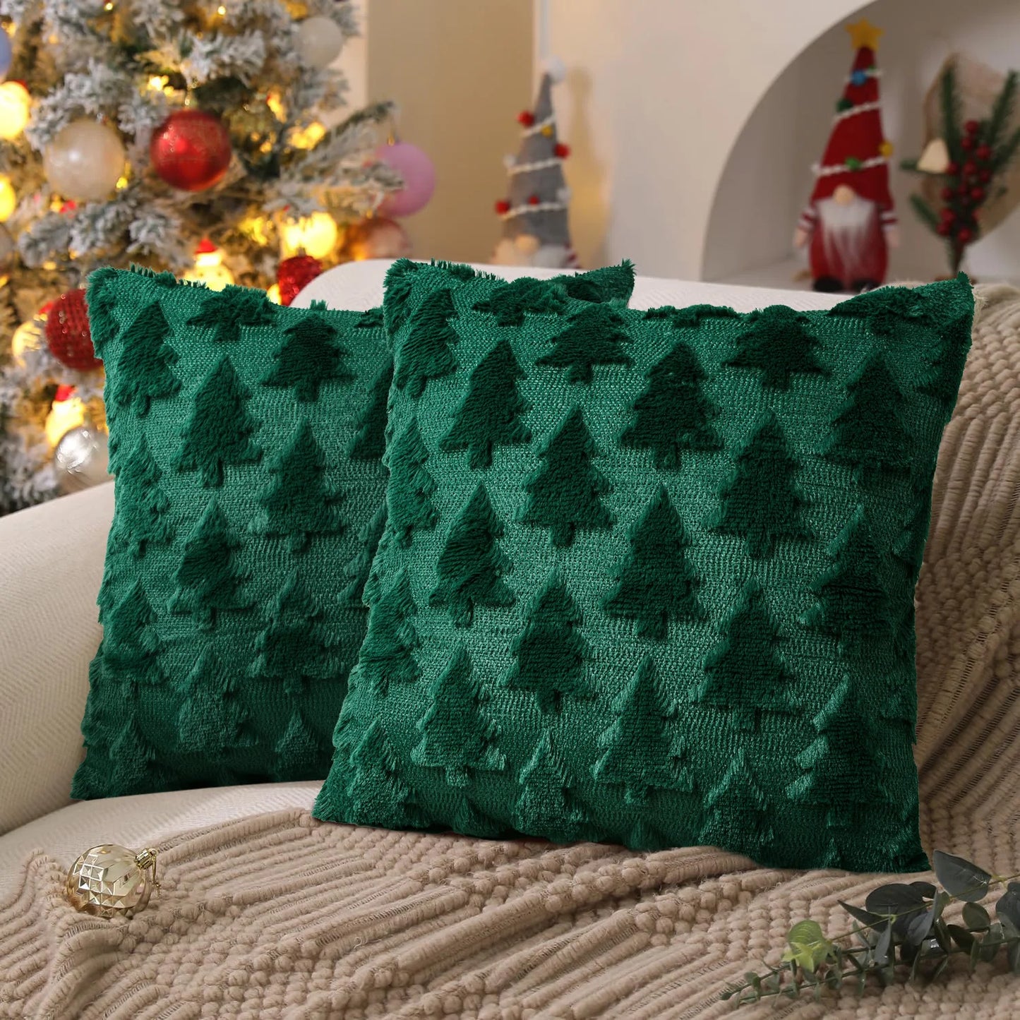 Two green textured pillows with tree pattern on a couch in a festive setting with Christmas decorations.