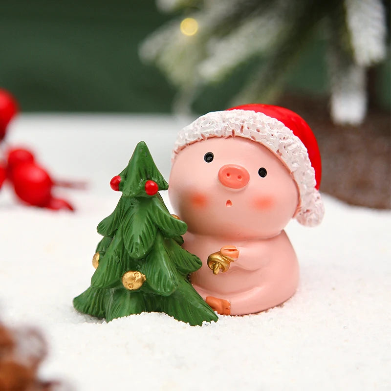 Decorative pig figurine wearing a Santa hat with a small Christmas tree, surrounded by snow and red berries.