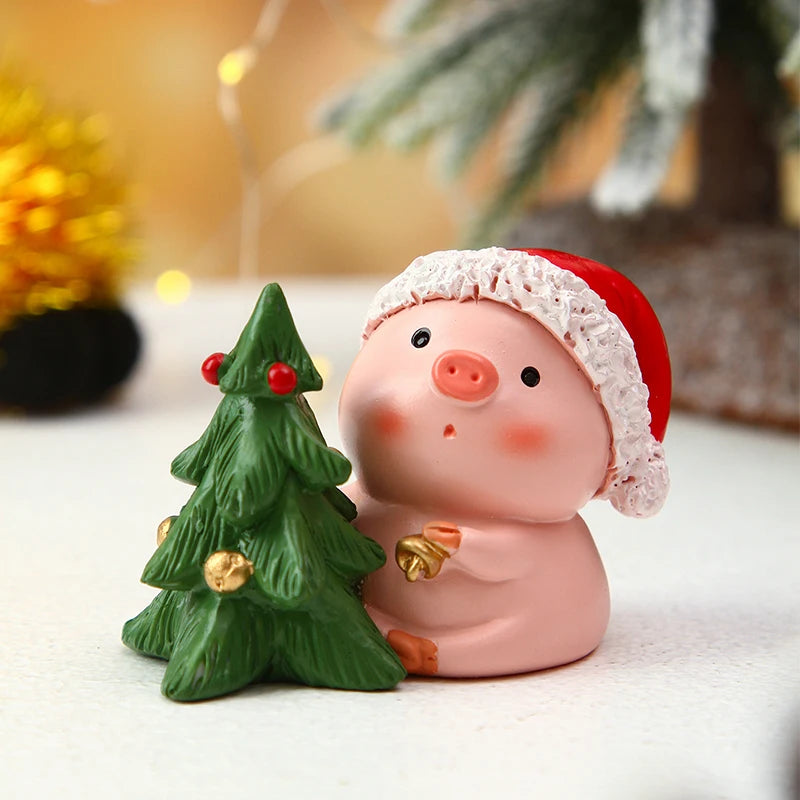 Decorative pig figurine with a Santa hat and small Christmas tree on a white surface.