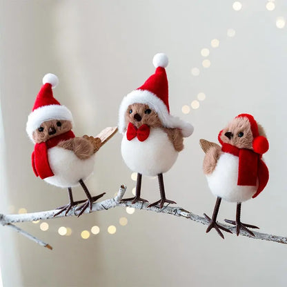 Three toy birds wearing Santa hats and scarves on a branch with a soft, blurred background.