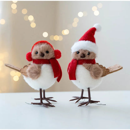 Two festive bird figurines wearing Santa hats and scarves against a blurred light background.